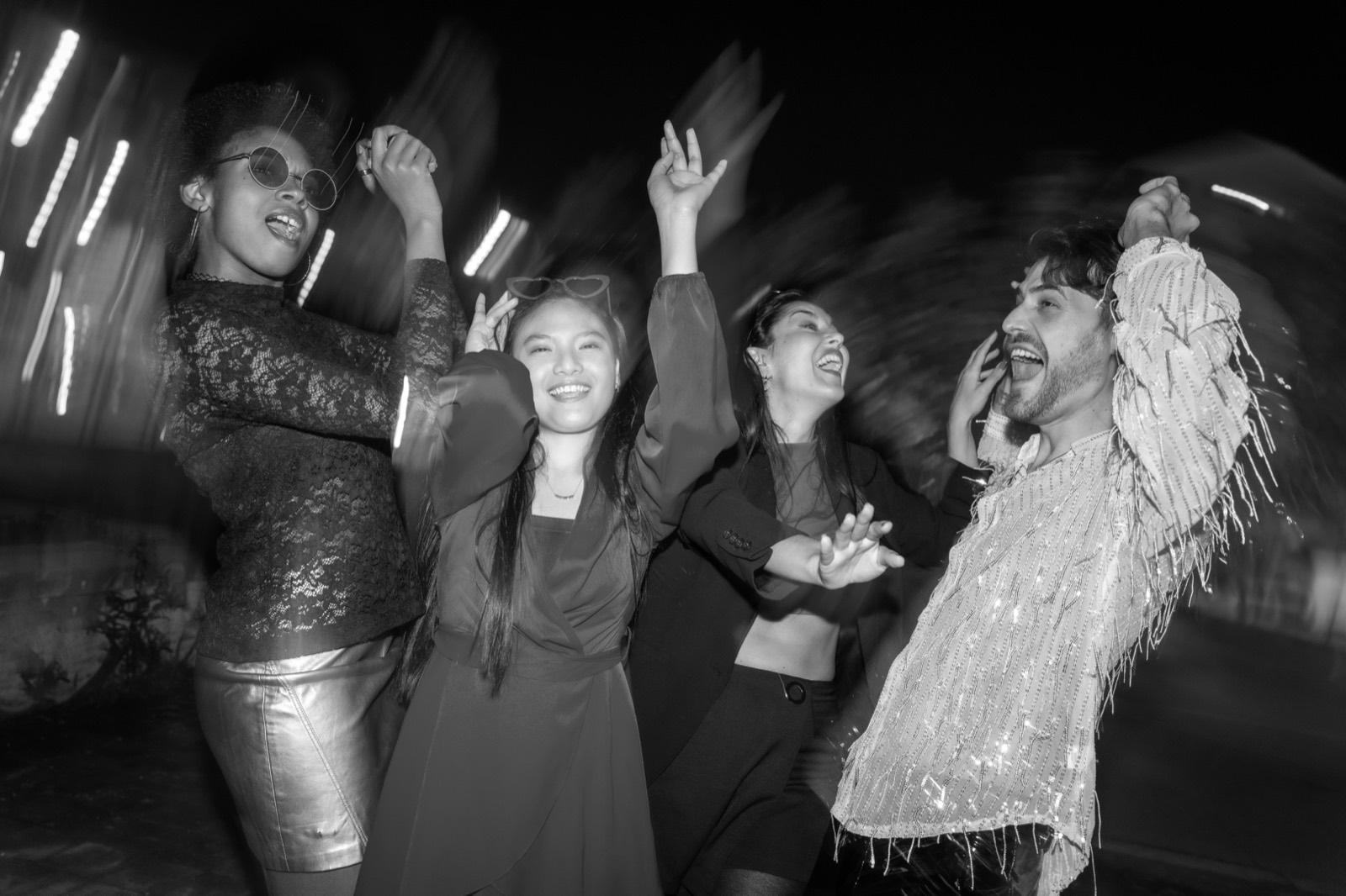 Four friends dancing together on a night out in the city.